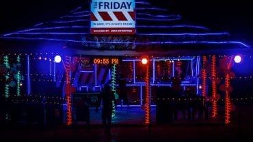 a man standing in front of a building covered in christmas lights